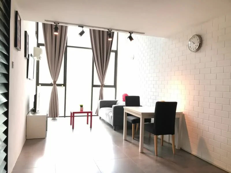 Living features: grey fabric sofa, white wall with exposed brick texture, grey tile flooring, recessed LED downlights, track lighting, floor-to-ceiling windows, sheer curtains, wall clock, TV console, small red coffee table, dining table with two black upholstered chairs, air conditioning unit; style: modern.