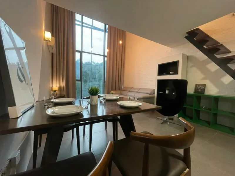 Dining features: wooden dining table, 4 dining chairs, large window with sheer curtains, grey tiled flooring, decorative plant on table, wall-mounted sconce lighting, green shelving unit, sofa in background, staircase in background, white painted walls, exposed brick wall, pendant lighting; style: modern; view: garden.