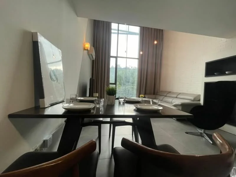 Dining features: wooden dining table, 4 dining chairs, white plates, cutlery, decorative plant in pot, pendant lighting, grey tiled flooring, wall-mounted air conditioning unit; style: modern; view: garden. Living features: sectional sofa in light grey, wall-mounted TV, large windows with sheer curtains, decorative wall sconce, exposed brick wall, coffee table; style: modern; view: garden.