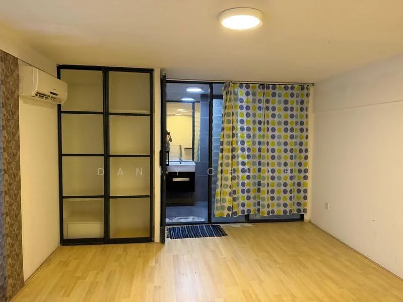 Room features: laminate flooring, white painted walls, ceiling light, wall-mounted split AC, glass sliding door, curtains with polka dot pattern, open space layout, visible bathroom area; style: modern.