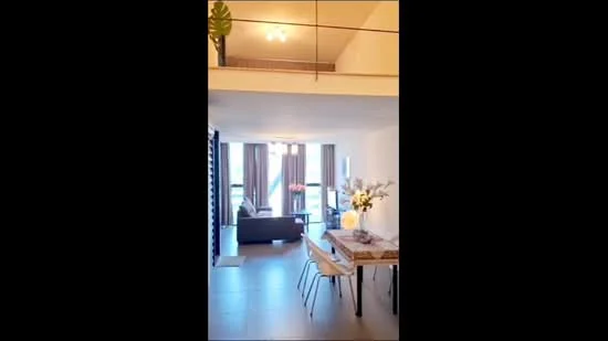 Living features: floor-to-ceiling windows, sliding glass door, curtains, sofa in dark color, coffee table, area rug, decorative plants, wall-mounted lighting, open layout, tile flooring, dining table with chairs, decorative vase with flowers; style: modern; view: garden. Room features: white painted walls, recessed ceiling lights.