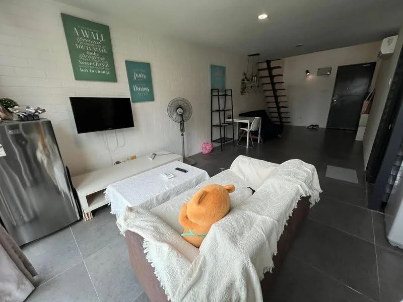 Living features: grey tile flooring, white painted walls, wall-mounted TV, 3-seater fabric sofa in brown, white throw blankets, decorative wall art, standing fan, coffee table, area rug, open shelving, staircase in background, doorway leading to hallway; style: modern.