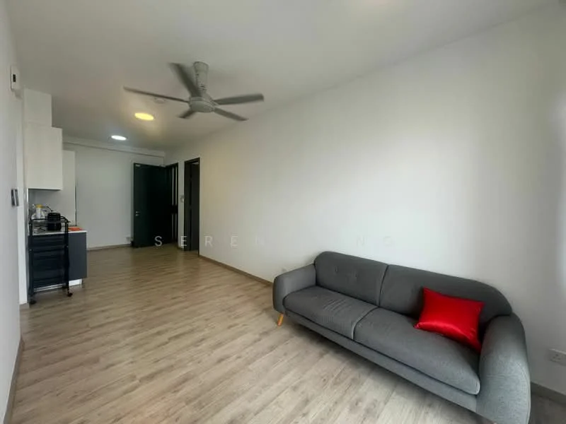 Living features: grey fabric sofa, red decorative cushion, light wood laminate flooring, white painted walls, ceiling fan, recessed ceiling lights, open layout, kitchenette visible in background, doorway leading to other rooms; style: modern.