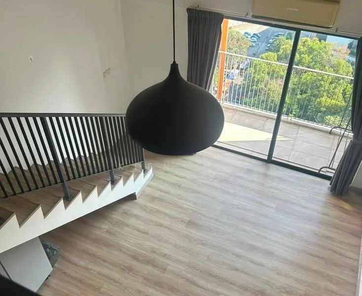 Room features: wooden flooring, large glass sliding door, balcony access, black pendant light, staircase with wooden steps and black railing, floor-to-ceiling windows, curtains, view of greenery; style: modern; view: garden.
