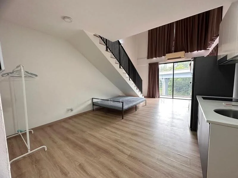 Room features: wooden flooring, white painted walls, large windows with sheer curtains, black metal staircase, air conditioning unit, double bed frame without mattress, clothes rack, kitchenette with sink, refrigerator, open layout; style: modern; view: garden.