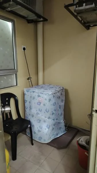 Laundry features: washing machine covered with fabric, plastic chair, tile flooring, yellow painted walls, window with frosted glass, drainage pipe, power outlet, small mat on the floor.