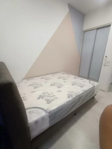 Bedroom features: queen-size bed, upholstered headboard, light wood flooring, white painted walls, accent wall with geometric design, sliding mirror wardrobe, natural light from window, minimalist decor; style: modern.