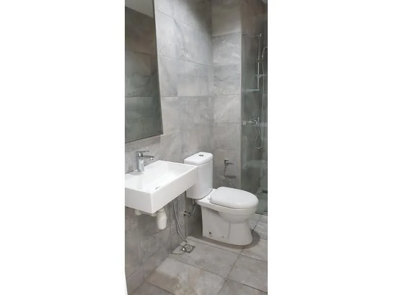 Bathroom features: grey tiled walls, grey tiled flooring, wall-mounted sink, chrome basin mixer faucet, one-piece toilet, glass shower enclosure, rain shower head, framed mirror; style: modern.
