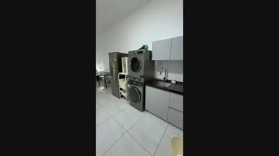 Laundry features: grey cabinetry, black countertop, stainless-steel fridge, stacked washer and dryer, white walls, tile flooring, single-bowl stainless-steel sink, modern faucet; style: modern.