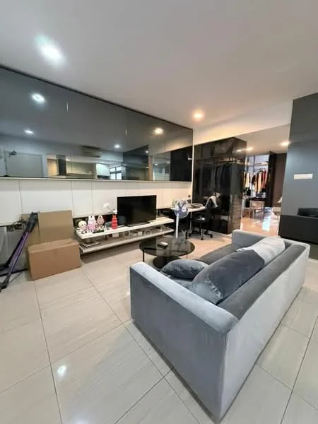Living features: grey fabric sofa, glass coffee table, wall-mounted TV, black feature wall, mirrored wall, light-colored tiled flooring, recessed ceiling lights, decorative items on shelves, open layout, storage cabinets, boxes for storage; style: modern.