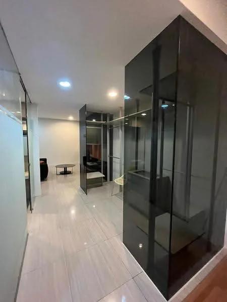 Room features: glossy white tile flooring, glass partition walls, recessed ceiling lights, open layout, neutral wall colour, modern design elements, minimalist decor, built-in shelving units; style: modern.