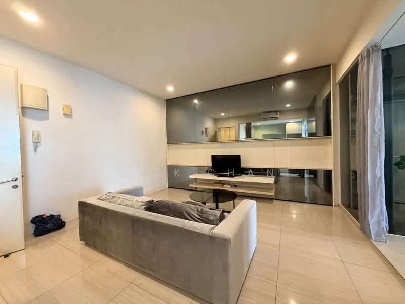 Living features: grey fabric sofa, coffee table, wall-mounted TV, white media console, mirrored wall, recessed downlights, tile flooring, sliding glass door, curtains, open layout to kitchen, decorative plant; style: modern.