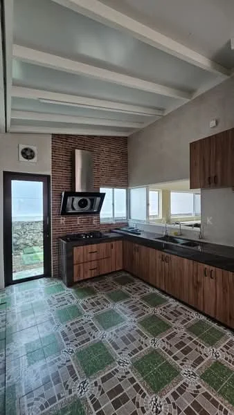 Kitchen features: brown wooden cabinetry, black countertop, stainless-steel range hood, 4-burner gas hob, built-in oven, green and white patterned floor tiles, exposed brick wall, large windows for natural light, sliding glass door, white painted ceiling with exposed beams; style: modern; view: garden.