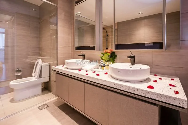 Bathroom features: double-sink vanity with stone countertop, two round vessel sinks, chrome basin mixer faucets, wall-mounted mirror, lighted mirror, white one-piece toilet, tile flooring, grey tiled walls, decorative rose petals on countertop, built-in cabinetry below sinks, recessed downlights; style: modern.