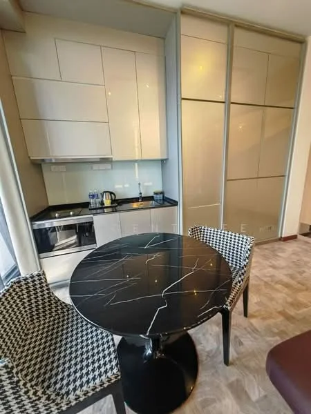 Kitchen features: black marble dining table, two patterned dining chairs, white high-gloss cabinetry, black countertop, built-in oven, stainless-steel kettle, glass water bottles, microwave, recessed lighting, tile flooring; style: modern.