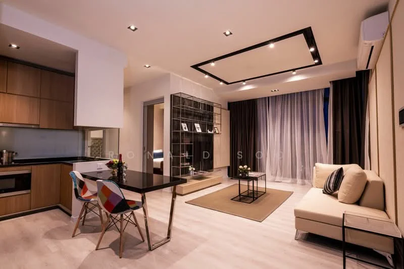 Living features: light wood flooring, cream painted walls, tray ceiling with recessed lighting, floor-to-ceiling windows with sheer curtains, beige fabric sofa, glass coffee table, decorative area rug, wall-mounted artwork, open shelving unit, dining table with colorful chairs, kitchenette with wooden cabinetry, stainless-steel sink, built-in oven, induction cooktop; style: modern.