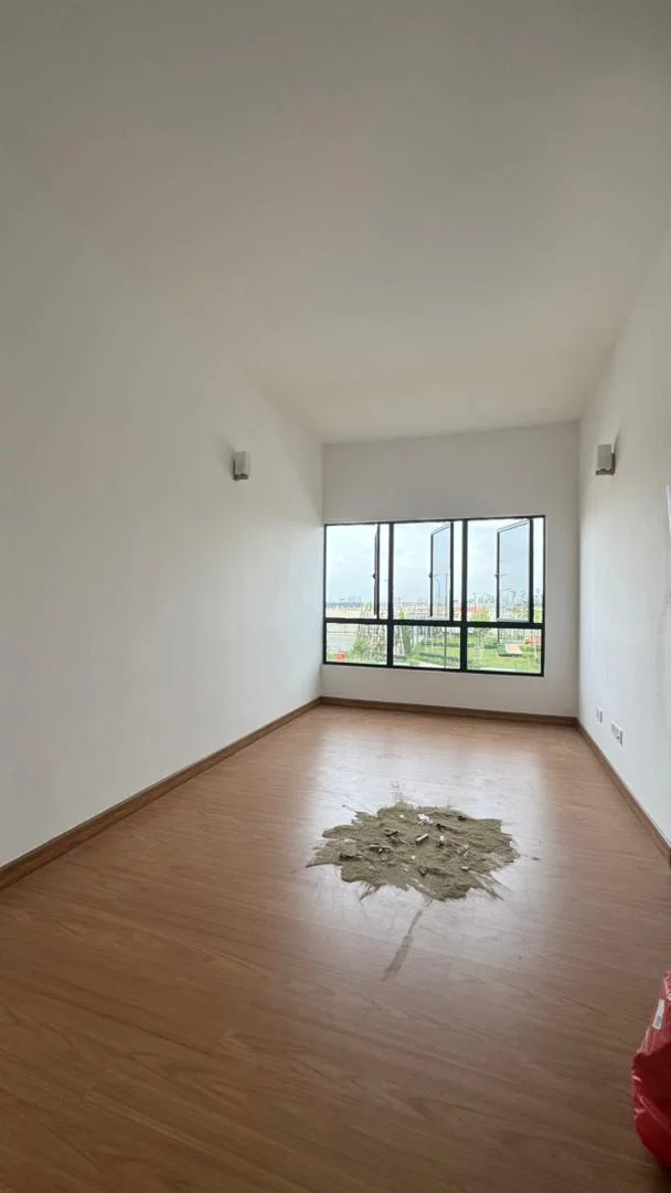 Room features: white painted walls, laminate flooring, large window with city view, two wall-mounted lights, visible floor damage, high ceiling; view: city.
