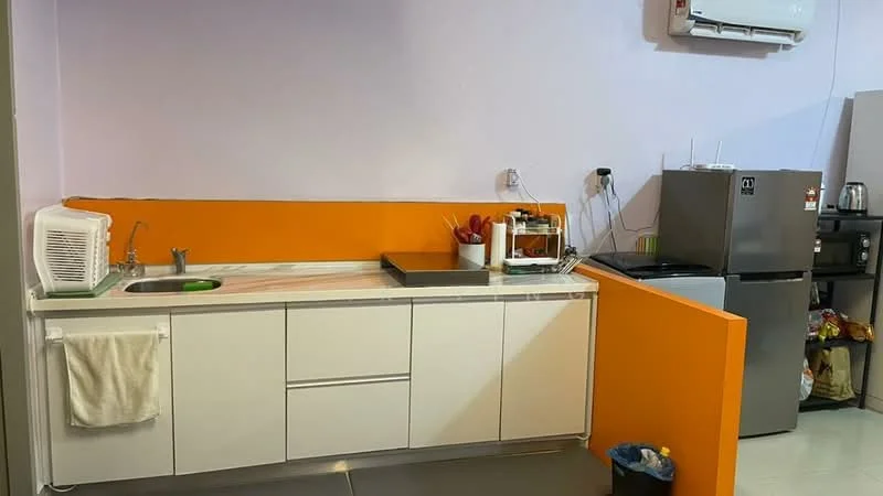 Kitchen features: single-bowl stainless-steel sink, chrome pull-down faucet, white cabinetry, orange accent wall, marble countertop, built-in oven, stainless-steel fridge, microwave, kitchen utensils on countertop, wall-mounted air conditioning unit, flooring with tiles, waste bin; style: modern.