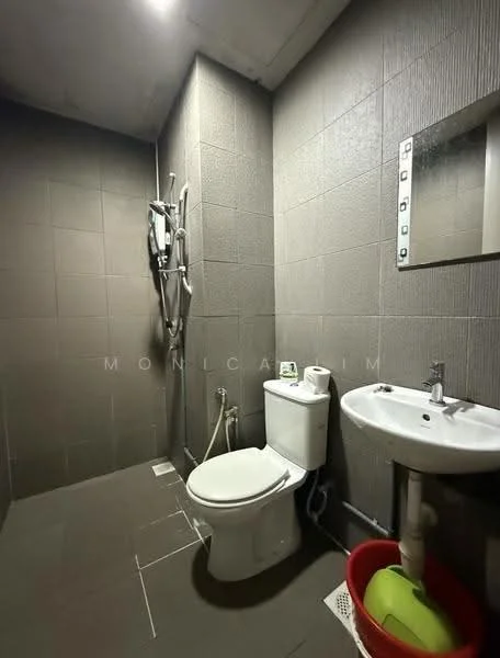 Bathroom features: grey tiled walls, grey tiled flooring, walk-in shower with glass partition, chrome handheld showerhead, chrome wall-mounted faucet, white sink with pedestal, one-piece toilet, mirror above sink, towel rack, red storage basket; style: modern.