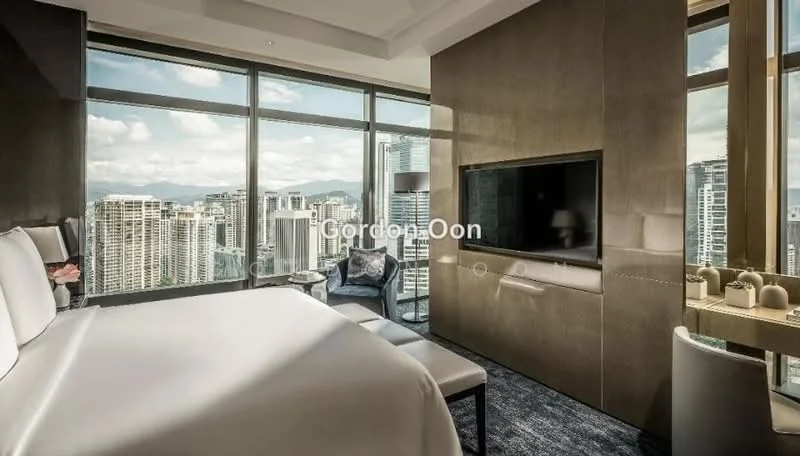Bedroom features: king-size bed with white bedding, floor-to-ceiling windows, city skyline view, wall-mounted TV, grey accent wall, light grey carpet flooring, side chair, decorative table with vases, built-in cabinetry, recessed lighting; style: modern; view: city.