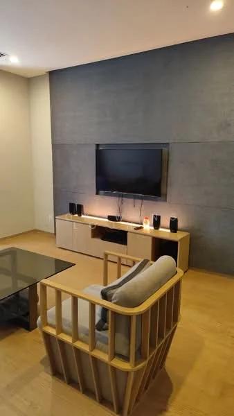 Living features: light wood flooring, grey accent wall, flat-screen TV mounted on wall, wooden TV console, black speakers, glass coffee table, armchair with wooden frame, recessed ceiling lights; style: modern.