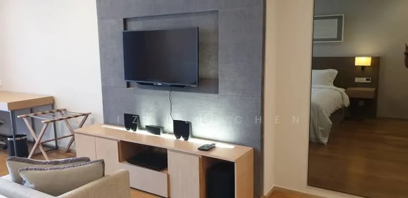 Living features: wall-mounted TV, light wood TV console, grey accent wall, recessed lighting, wooden flooring, sofa with light fabric upholstery, decorative mirror, side table, bedroom visible in background; style: modern.