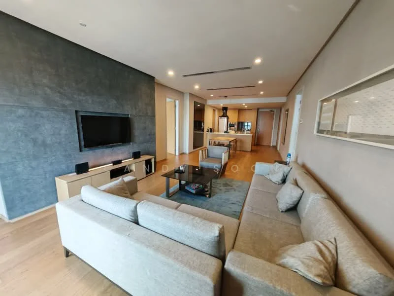Living features: light wood flooring, grey accent wall, wall-mounted TV, light grey fabric sofa, coffee table, decorative wall art, recessed ceiling lights, open layout to kitchen, large windows, neutral wall color; style: modern. Kitchen features: kitchen island, stainless-steel appliances, wood cabinetry, granite countertop, open-plan layout, recessed lighting; style: modern.