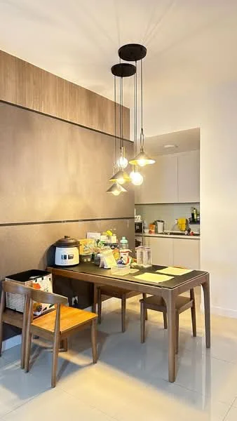 Dining features: wooden dining table, 4 dining chairs, pendant lighting with multiple bulbs, cream painted walls, glossy tile flooring, kitchen area visible in background, kitchen cabinets in light colour, rice cooker on the table, decorative items on the table; style: modern.