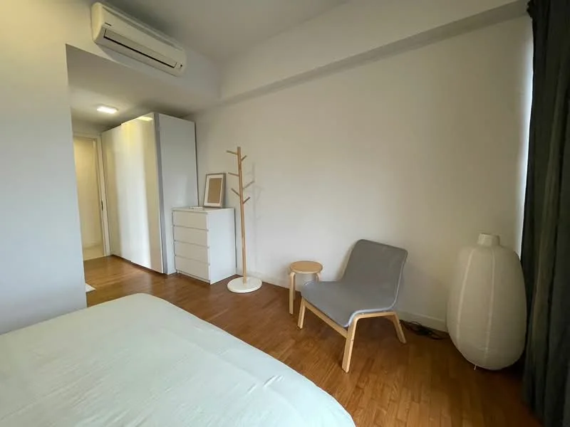 Bedroom features: wooden flooring, white painted walls, 1 wall-mounted split AC, queen-size bed, bedside table, grey upholstered chair, white dresser, clothes rack, floor lamp, curtains, decorative wall art; style: minimalist.