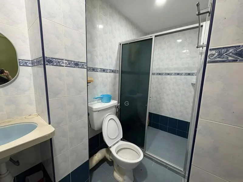 Bathroom features: white tiled walls, blue decorative border tiles, light blue sink, single-sink vanity, one-piece toilet, glass shower enclosure, shower head, grey floor tiles, mirror, wall-mounted soap holder.