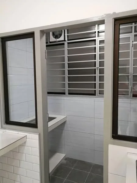 Room features: grey tiled flooring, white tiled walls, sliding glass door, metal grilles on windows, built-in countertop, corner shelf, ventilation fan, natural light from window; style: modern.