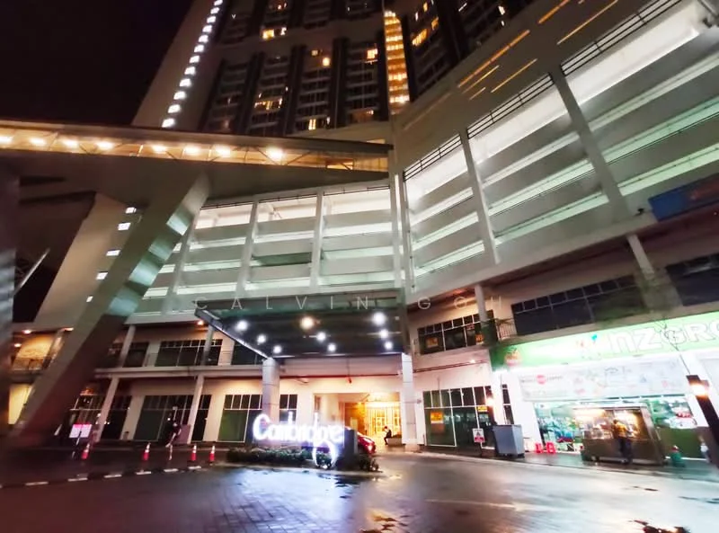 Exterior type: high-rise condominium; features: modern facade with glass and concrete, covered entrance with awning, illuminated signage, multiple levels of parking, large windows on upper floors, night lighting, surrounding driveway, adjacent retail space, manicured landscaping at entrance; style: modern.