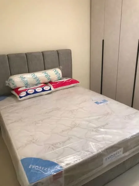Bedroom features: queen-size bed, upholstered headboard in grey, mattress with protective cover, decorative pillows, built-in wardrobe with sliding doors, neutral wall color, laminate flooring; style: modern.