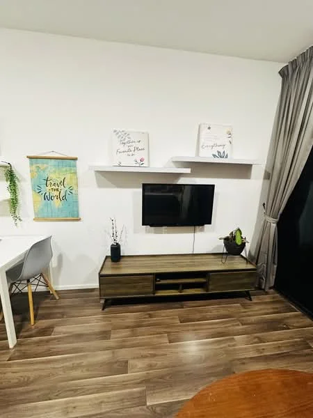 Living features: wooden flooring, white painted walls, wall-mounted TV, TV console in dark wood, decorative wall shelves, framed artwork on walls, curtains in grey fabric, dining table with white chairs, indoor plant in ceramic pot; style: modern.