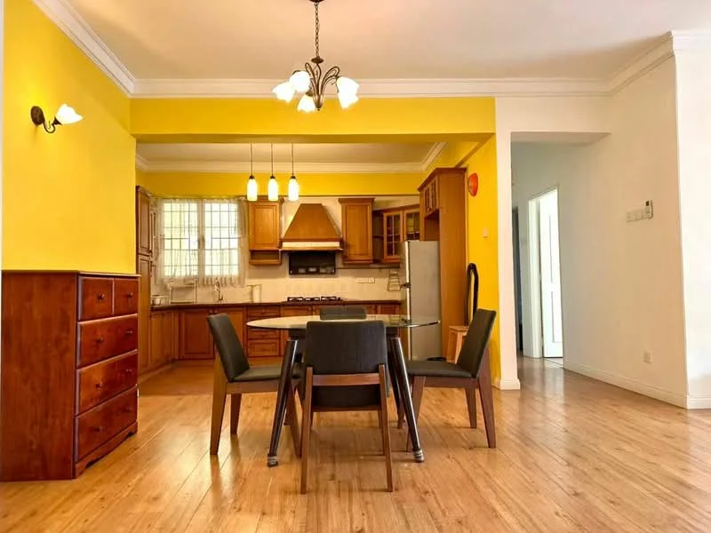 Dining features: yellow painted walls, wooden flooring, dining table with four chairs, chandelier with three bulbs, wall-mounted sconce, open layout to kitchen, crown moulding, window with grid pattern, built-in cabinetry, stainless-steel fridge, gas stove with hood; style: modern. Kitchen features: wooden cabinetry, granite countertop, stainless-steel sink, chrome faucet, built-in oven, freestanding range oven, tile backsplash; style: modern.