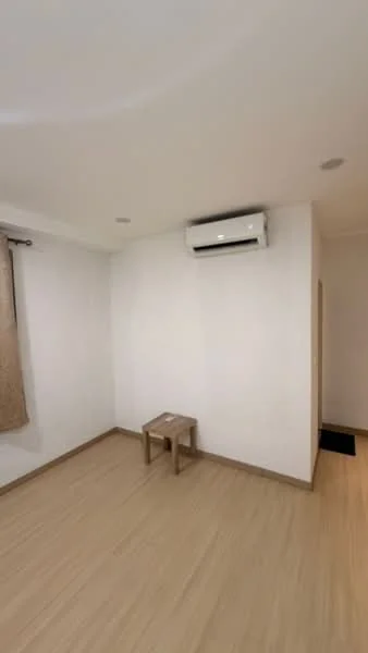Room features: light wood laminate flooring, white painted walls, 1 wall-mounted split AC, single wooden stool, curtains on window, recessed ceiling lights; style: minimalist.
