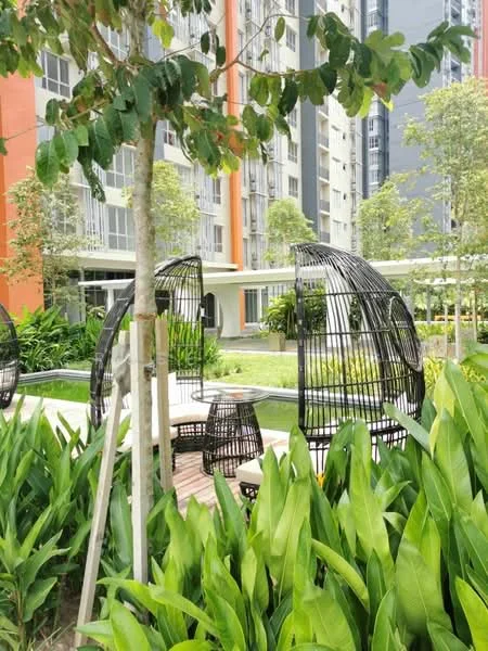 Exterior type: high-rise condominium; features: landscaped garden with greenery, decorative outdoor seating, swimming pool visible in background, manicured lawn, mature trees, modern architectural design, surrounded by residential buildings; style: modern.