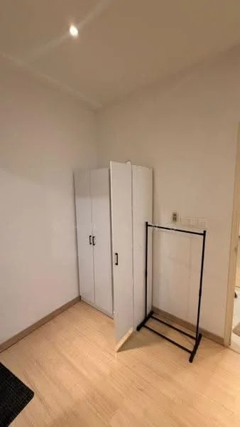 Room features: white painted walls, light wood flooring, built-in wardrobe with sliding doors, freestanding clothing rack, recessed lighting; style: minimalist.