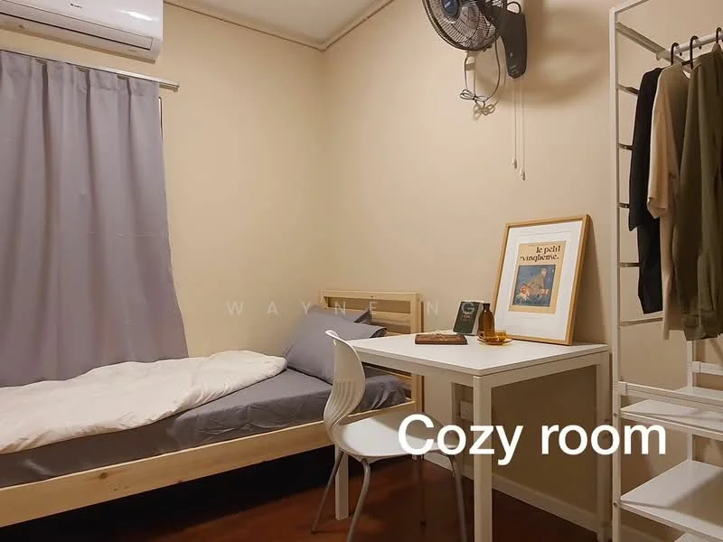 Bedroom features: single bed with grey bedding, white wall, wooden bed frame, white desk, white chair, clothes rack with hanging clothes, curtains in grey, ceiling fan, wooden flooring, decorative framed artwork; style: cozy.
