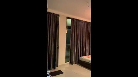 Room features: floor-to-ceiling windows, dark curtains, light-colored walls, tile flooring, bed with bedding, nightstand, decorative lighting; style: modern.