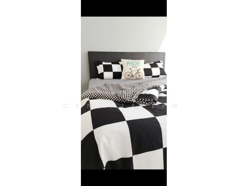Bedroom features: king-size bed, black and white checkered bedding, decorative pillow with bicycle graphic, grey upholstered headboard, white walls, natural light from window, bedside table, area rug; style: modern.