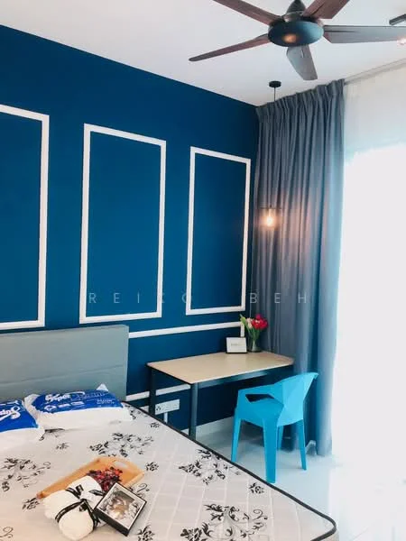 Bedroom features: blue accent wall with white paneling, white painted walls, queen-size bed with grey upholstered headboard, white bedding with black floral pattern, wooden flooring, 5-blade ceiling fan, desk with chair, blue plastic chair, curtains, natural light from window; style: modern.