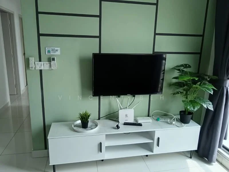 Living features: green painted walls with geometric pattern, white tiled flooring, wall-mounted flat-screen TV, white TV console with open shelving, decorative plant in black pot, small potted plant on TV console, grey curtains, power outlet on wall, cable management box on console; style: modern.
