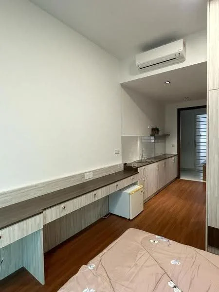 Room features: wooden flooring, white painted walls, wall-mounted split AC, built-in cabinetry, countertop with storage, small fridge, recessed downlights, kitchenette area; style: modern.