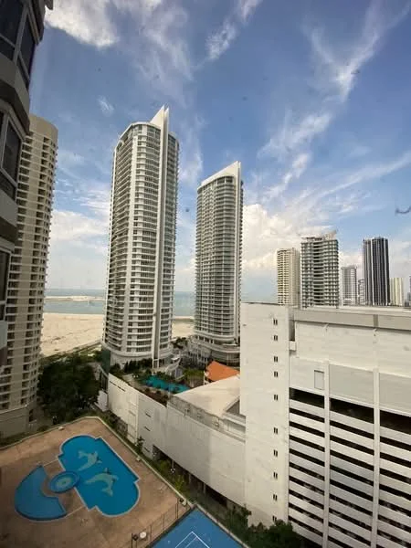 Exterior type: high-rise condominium; features: glass curtain wall, approximately 20-storey high-rise, infinity pool, swimming pool deck, children's playground, tennis court, manicured lawn, surrounded by mature greenery, sea view, urban context; style: modern.