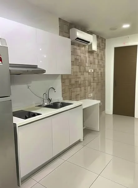 Kitchen features: white glossy cabinetry, stainless-steel fridge, single-bowl stainless-steel sink, chrome pull-down faucet, black cooktop, white countertop, textured wall tiles in beige, recessed LED downlights, wall-mounted split AC, large format glossy floor tiles; style: modern.
