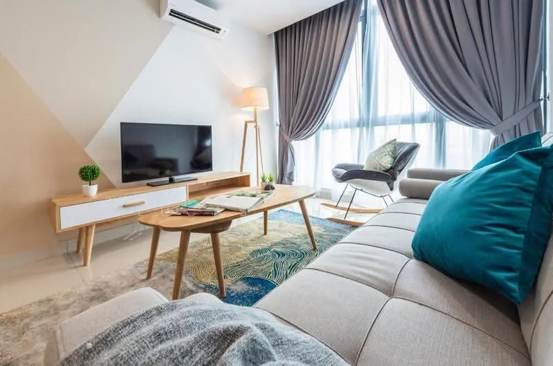 Living features: light grey fabric sofa, blue decorative cushion, wooden coffee table, area rug with abstract pattern, wall-mounted flat-screen TV, wooden TV console, floor lamp, rocking chair, floor-to-ceiling windows, grey curtains, white walls, air conditioning unit; style: modern; view: city.