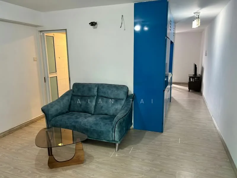 Living features: blue fabric sofa, glass coffee table, laminate flooring, white painted walls, recessed downlights, TV console, open layout, wall-mounted TV, decorative wall panel; style: modern. Room features: doorway leading to bathroom, light fixture in hallway.
