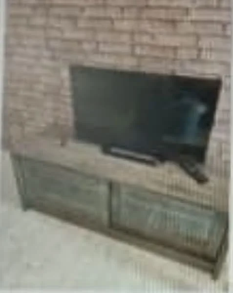 Living features: exposed brick wall, TV mounted on wall, wooden TV console, glass-fronted cabinet, neutral carpet flooring; style: modern.