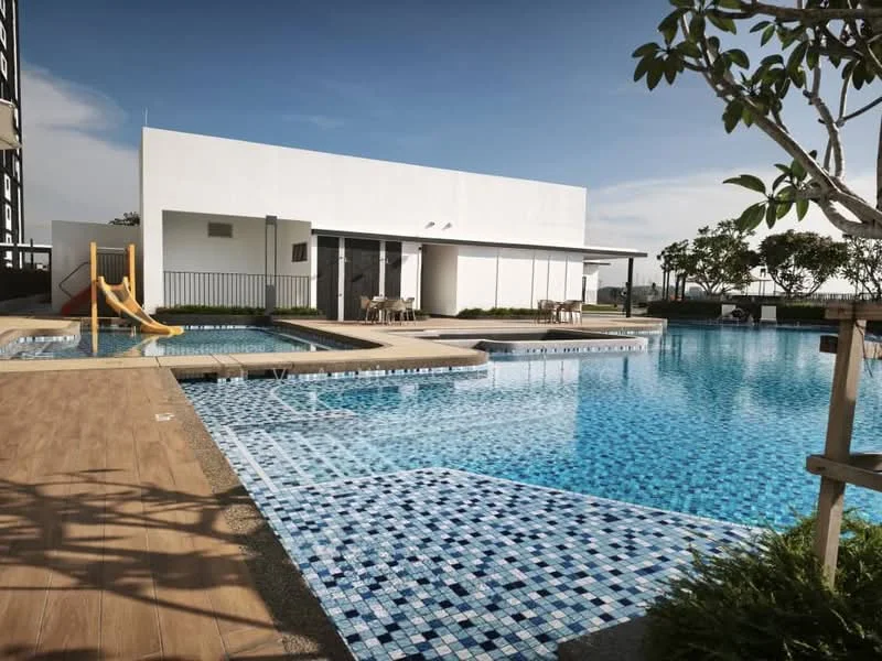 Exterior type: swimming pool deck; features: infinity pool, children's slide, pool deck with loungers, tiled pool surface with blue mosaic, landscaped greenery, wooden decking, seating area with tables and chairs, surrounding fencing, clear sky, modern architectural design; style: modern.